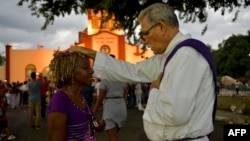 Un sacerdote bendice a un peregrino durante la procesión a El Rincón en adoración a San Lázaro. Yamil Lage/AFP