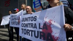 Opositores al régimen de Nicolas Maduro en Venezuela portan un cartel que reza: "Juntos contra la tortura", frente a la oficina de la ONU en Caracas.