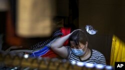Una mujer se protege del coronavirus en una fábrica de textiles en Beijing. (AP/Andy Wong).