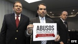 Tomás Guanipa (c), diputado del partido Primero Justicia de Capriles, muestra un cartel con el lema "Abusos electorales".
