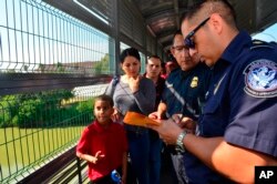 Funcionarios de Frontera procesan a una familia cubana en el Puente Internacional de Nuevo Laredo, Texas el 10 de julio de 2019 (Foto AP /Salvador González).