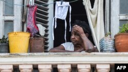 Una mujer mira a la calle desde su balcón en La Habana. 