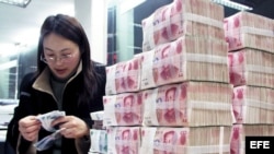 Una mujer cuenta billetes de banco chinos en una caja de ahorros de Hai'an, provincia de Jiangsu al este de China.