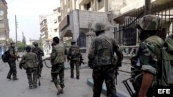 Imagen facilitada por la agencia siria de noticias SANA de soldados sirios patrullando una calle de Harasta, al este de Damasco, Siria. 