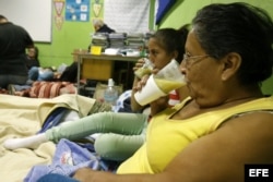 Dos mujeres beben un caldo en uno de los albergues facilitados para los vecinos afectados en incendio Valparaiso,