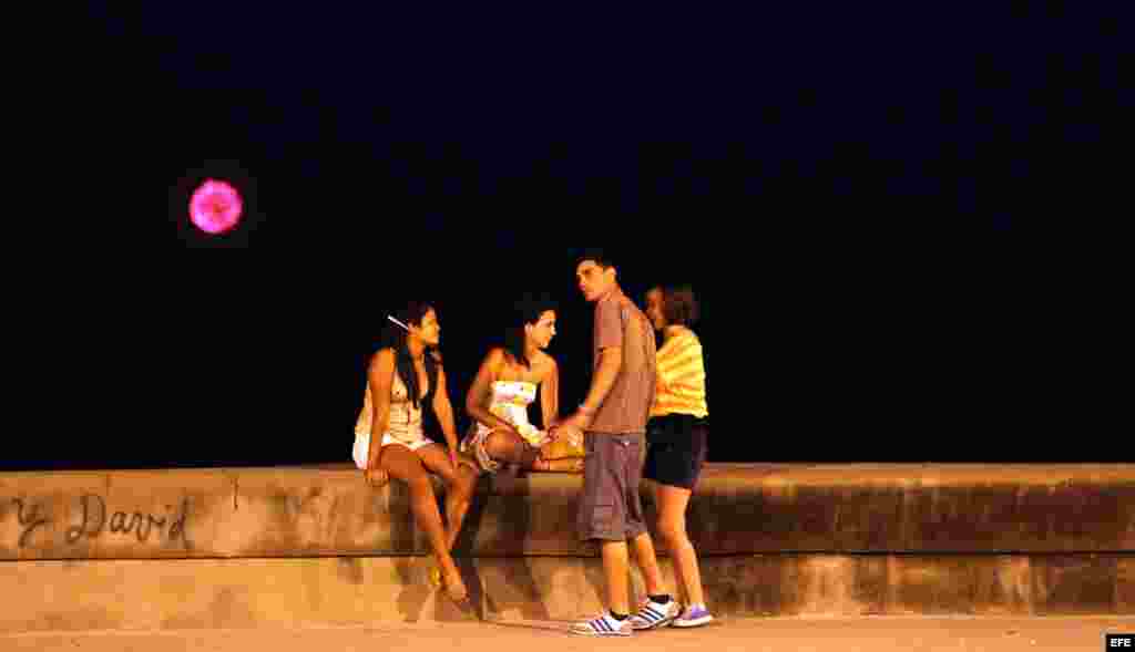 Jóvenes conversan mientras en el fondo se observan los fuegos artificiales lanzados por una flotilla del exilio cubano para conmemorar el vigésimo aniversario del hundimiento del Remolcador 13 de marzo.