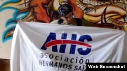 Artista cubano sotiene la bandera de la Asociación Hermanos Saíz.