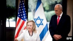 El presidente israelí Simón Peres (d) observa como la secretaria de Estado de EEUU Hillary Clinton (i) firma el libro de invitados durante una reunión en Jerusalén (Israel), hoy, lunes 16 de julio de 2012. EFE/ABIR SULTAN