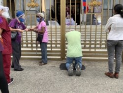 Un ciudadano se arrodilla a las puertas de la iglesia Nuestra Señora de Coromoto, ubicada el oeste de Caracas, Venezuela. Marzo 31, 2021.