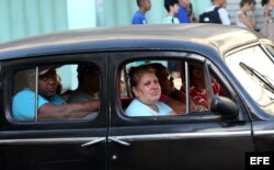 Varias personas van en un taxi de fabricación estadounidense en una calle de La Habana (Cuba).
