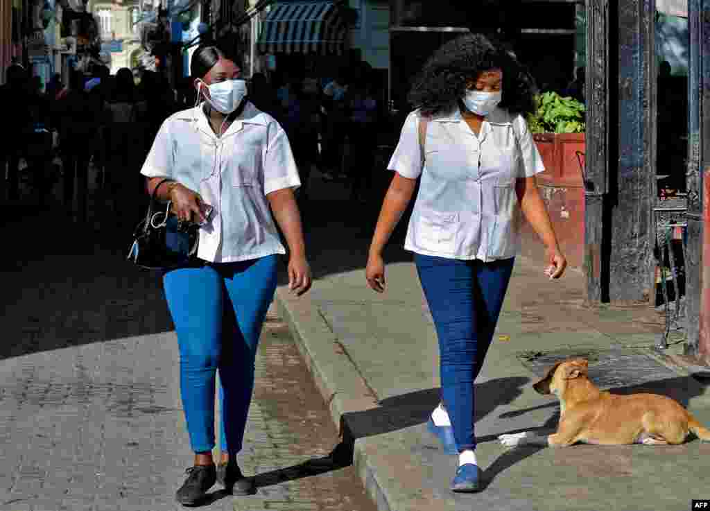  Las mujeres usan m&#225;scaras faciales mientras caminan por las calles de La Habana