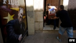 Dos hombres cargan cajas de cerveza en un restaurante privado un día después de la inhumación de las cenizas de Fidel Castro.