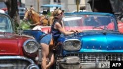 Una turista posa para una foto en La Habana Vieja. Al fondo, uno de los carruajes que pasean a los visitantes extranjeros. 