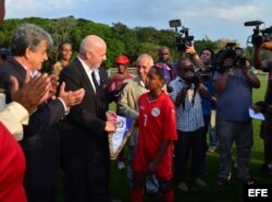 Infantino recibe de manos de una niña futbolista el gallardete de la Federación Cubana de Fútbol.