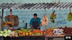 Un hombre vende frutas, viandas y verduras en un mercado agropecuario