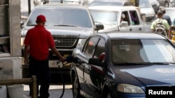 Un trabajador habilita un auto en una gasolinera de la estatal PDVSA este viernes en Caracas.
