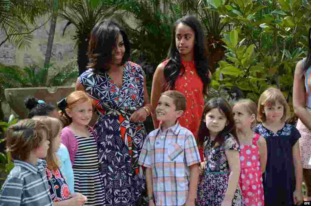La primera dama estadounidense, Michelle Obama (c-i), y su hija Malia (c-d) posan junto a un grupo de niños durante una ceremonia en La Habana Vieja.