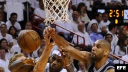 El jugador de Spurs Tim Duncan (d) bloquea un lanzamiento de LeBron James (c), de Heat, durante el primer partido por la final de la NBA en el American Airlines Arena de Miami, Florida