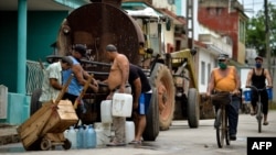Vecinos recogen agua de una pipa la mañana del martes en un barrio de San Antonio de los Baños, en la provincia de Artemisa (Yamil Lage/AFP).
