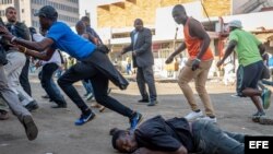 Un hombre cae al suelo tras ser disparado en la espalda por las fuerzas de seguridad durante una protesta organizada por simpatizantes del Movimiento por el Cambio Democrático (MDC) contra el conteo de votos tras las elecciones del país, en Harare, Zimbabue, el 1 de agosto de 2018. 