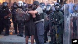 Policía abraza a uno de los manifestantes que ayudó a dispersar la multitud en Atlanta. AP Photo/John Bazemore