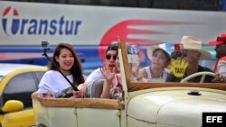 Turistas se toman una selfie durante un paseo en un auto clásico en La Habana.