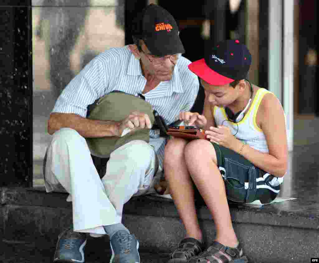 Dos personas navegan por internet a través de un dispositivo móvil desde una de las zonas habilitadas con Wi-Fi en La Habana (3 de julio, 2015).