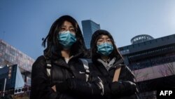 Transeúntes llevan máscaras el 23 de enero en un centro comercial de Pekín (Foto: Nicolas Asfouri/AFP).