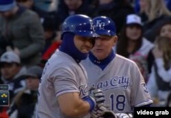 Kendrys Morales escucha al coach de primera tras impulsar dos con un sencillo.