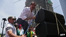 Juan Guaidó, presidente interino de Venezuela, sube a una tarima improvisada para hablarle al público en Caracas el 1ro de mayo de 2019. (AFP).