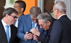 Raúl Castro observa el teléfono móvil del embajador ruso en Cuba, Mijail Kaminin.