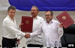 El delegado de las FARC en Cuba, Rodrigo Londoño Echeverri, alias "Timochenko" (d) y el presidente de Colombia, Juan Manuel Santos (i) junto a el presidente de Cuba, Raúl Castro (c) sostienen en sus manos el acuerdo de paz.