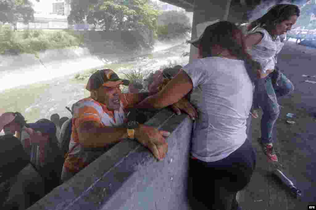 Una mujer ayuda a un hombre a subir de una pendiente a la orilla de una vía durante una protesta en contra del Gobierno venezolano hoy, miércoles 19 de abril de 2017, en Caracas (Venezuela). Centenares de opositores en distintos puntos de caracas se enfre
