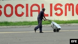 Un hombre camina frente a un cartel alusivo al socialismo en La Habana.