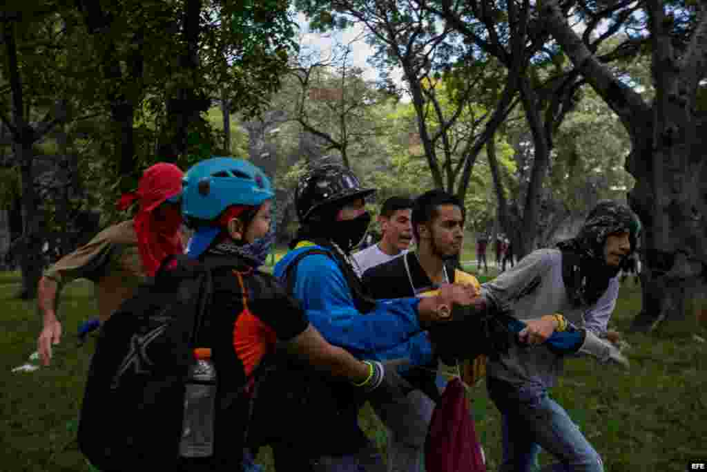 Un manifestante recibe ayuda de sus compañeros tras resultar herido durante un enfrentamiento con policías antimotines hoy, jueves 4 de mayo de 2017, en Caracas (Venezuela). Los cuerpos de seguridad dispersaron con gases lacrimógenos la manifestación de e