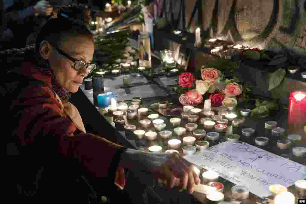 Una mujer enciende una vela en la Plaza de la República, en honor a las víctimas de los atentados de París. EFE