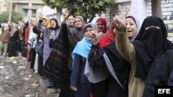 Numerosas mujeres hacen el signo de victoria con sus dedos mientras hacen cola para realizar su votación sobre el referéndum constitucional, a las puertas de un colegio electoral en Mahala, en la provincia de Gharbiya (Egipto).