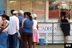 Varias personas hacen cola frente a una Casa de Cambio (CADECA).