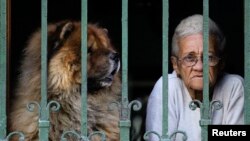Una mujer observada por su perro en la ventana de una vivienda en La Habana. REUTERS/Desmond Boylan/Archivo