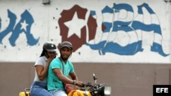 Una pareja de jóvenes cubanos viaja en una moto en una céntrica calle de La Habana (Cuba). El mestizaje racial creció en Cuba en los últimos años alcanzando al 26,6 por ciento de la población.