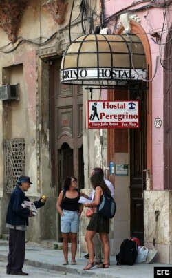 Un grupo de turistas conversan en la entrada de un hostal en La Habana.