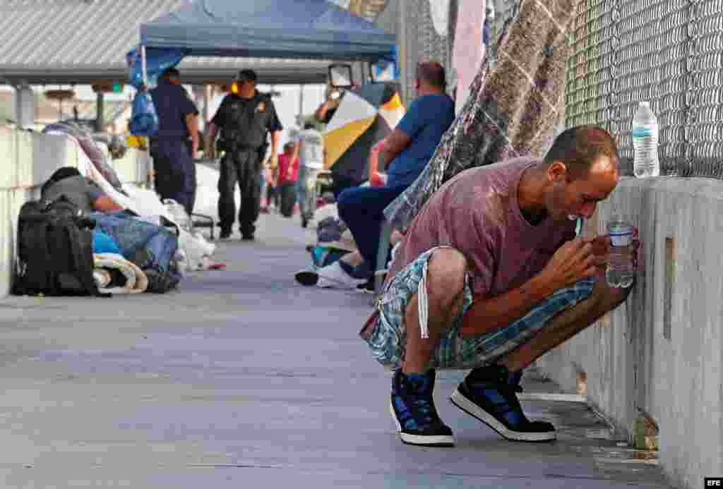 Un hombre se lava los dientes mientras aguarda en un puente junto a otros solicitantes de asilo de Guatemala y Cuba para poder entrar en EE.UU. en Matamoros (México) el 29 de junio de 2018. 