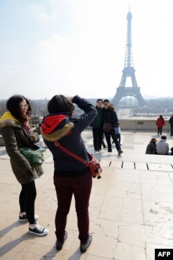 Turistas chinos posan con la Torre Eiffell de fondo.