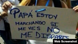 Una estudiante muestra una pancarta en la que le pide a su papá (un militar) que no le dispare.