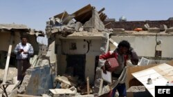 Varios yemenís intenta recuperar sus pertenencias entre los daños causados por un supuesto ataque aéreo saudí contra las milicias del movimiento chií de los hutíes en Saná, Yemen.