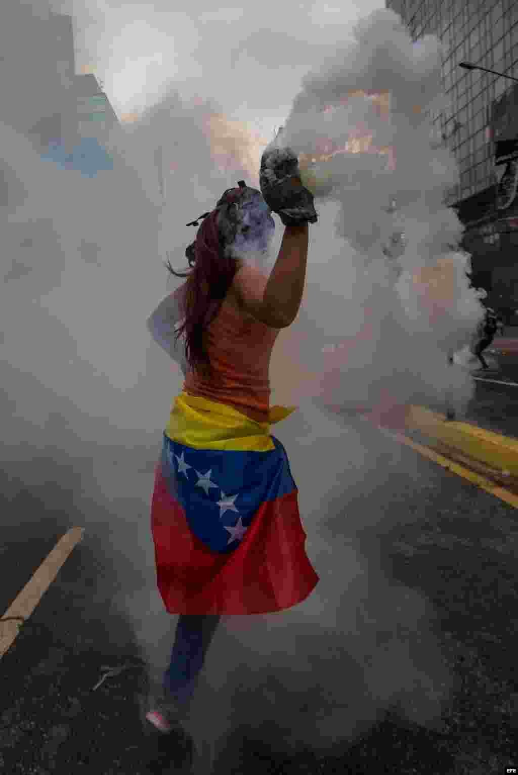 Una mujer destaca vestida con la bandera nacional entre los manifestantes que se enfrentaron con agentes de la Guardia Nacional Bolivariana el jueves 20 de abril de 2017, en Caracas (Venezuela).