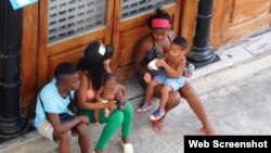 Mujeres sentadas con niños en brazos, a un lado de la calle Obispo, en la Habana Vieja. Foto: Ana León.