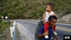 Un padre venezolano y a su hijo mientras recorren la vía hacía la ciudad de Bucaramanga desde Cúcuta (Colombia).