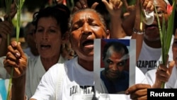 Reina Loyna Tamayo, madre de Orlando Zapata, sostiene una foto de su hijo fallecido a causa de una huelga de hambre. Foto tomada el 20 de junio de 2010. REUTERS/Desmond Boylan 