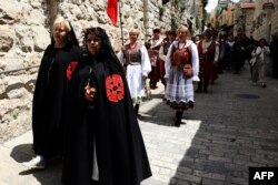 Damas de la orden de los Caballeros del Santo Sepulcro caminan por la Vía Dolorosa, en Jerusalén, durante la procesión del Viernes Santo. .